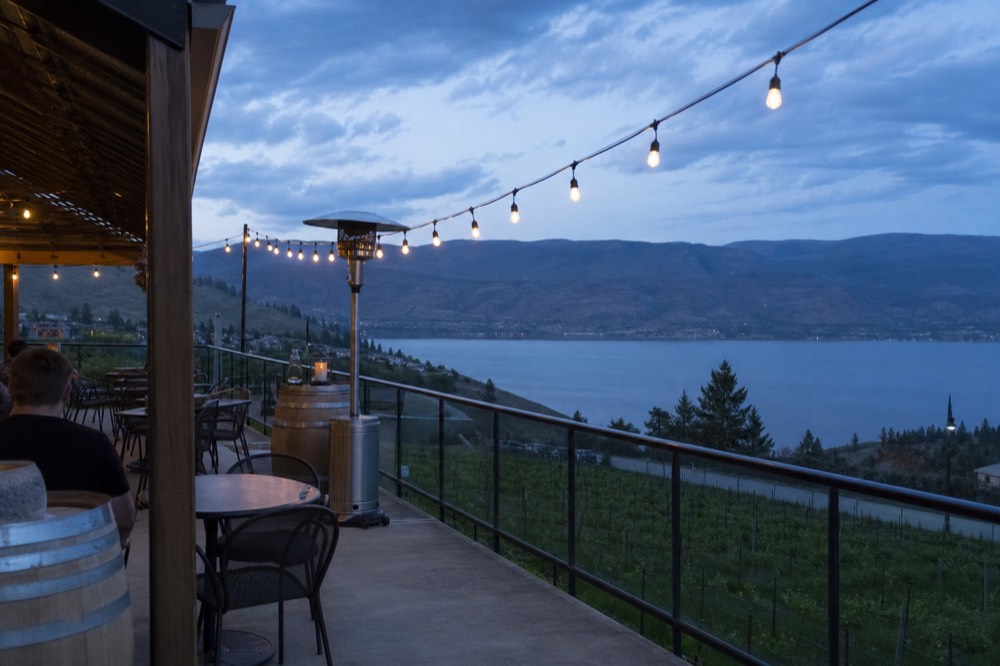 A hilltop winery terrace looking over vineyard rows and a blue lake, no logos, no people.